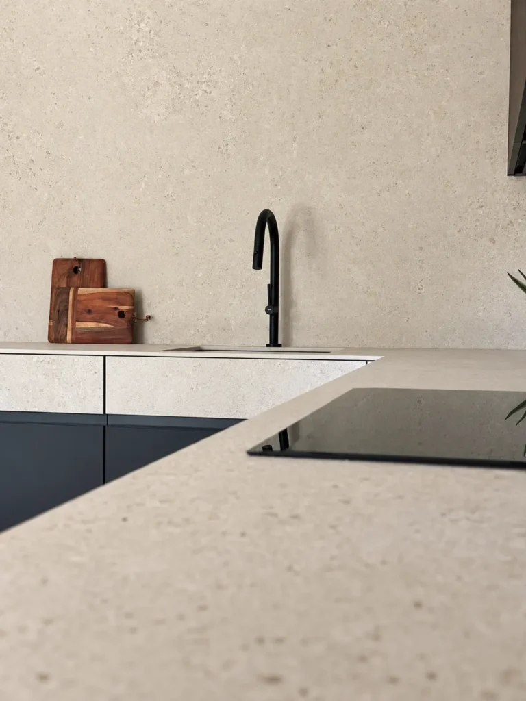 Vista general de cocina en L Gola Pura con muebles oscuros, módulos superiores en acabado de madera y columnas con electrodomésticos integrados.